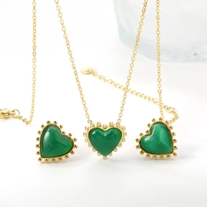 Detail view of heart pendants with green stone inlay and gold beaded edge on chains