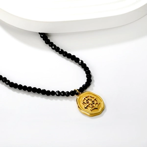 Oval spider web pendant necklace with faceted black beads in elegant minimalist display