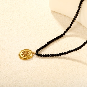 Golden spider web pendant necklace with black faceted beads in a vintage minimalist style