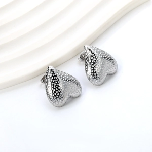 Detailed close-up of textured heart-shaped silver stud earrings with hammered finish