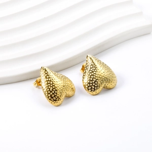 Detailed view of gold-plated heart earrings with unique pitted texture and metallic luster