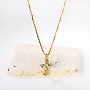 Collier pendentif croix dorée avec cristaux clairs sur une base de pierre texturée