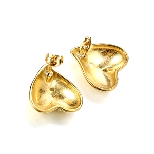 Macro view of gold heart stud earrings showing frosted texture and butterfly backings