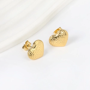 Detail of gold heart earrings featuring unique hammered texture and butterfly backings