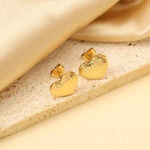 Hammered gold heart stud earrings on textured rock and satin background