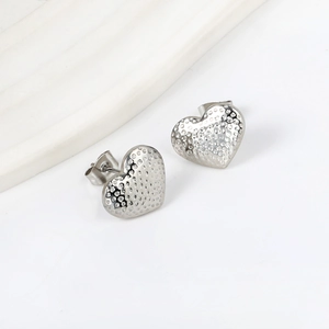 Close-up of silver heart stud earrings featuring a unique textured dotted pattern surface