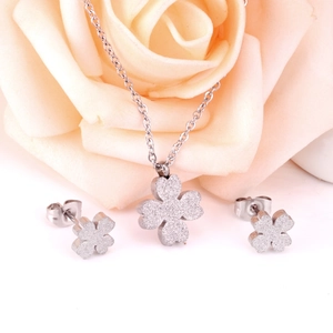 Silver frosted four-leaf clover jewelry set with necklace and earrings on rose background