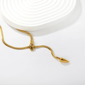Exaggerated 18K gold snake chain necklace with sparkling zircon head on a podium