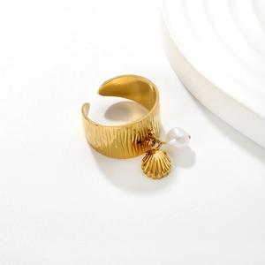 Detail of 18K gold open ring with vertical stripes, golden shell and white pearl charms