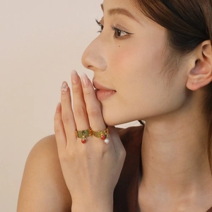 Hammered gold rings set with ladybug enamel pendant and white pearl on hand