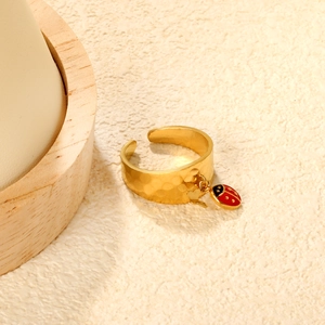 Close-up of 18K gold plated hammered ring with a red ladybug charm and tassel detail