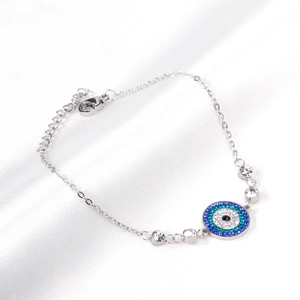 Macro shot of silver steel bracelet featuring a blue evil eye charm with micro-pave crystals