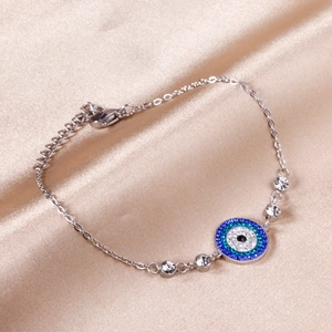 Detail of evil eye bracelet with blue crystals on champagne silk background
