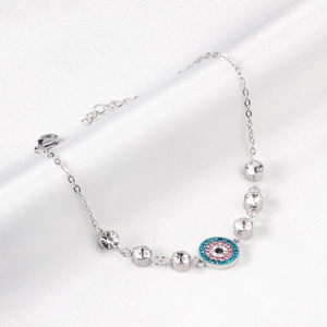 Close-up of silver evil eye bracelet with colorful zircons on white silk background