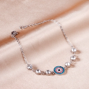 Silver evil eye bracelet with colorful rhinestones on elegant champagne satin backdrop