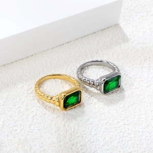 Detail of twisted rope band rings featuring emerald cut green zircon stones in gold and silver