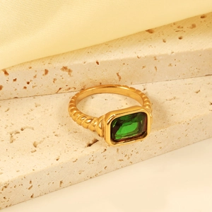 Macro detail of 18K gold twist band ring with rectangular emerald green gemstone