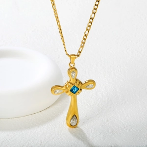 Collier croix dorée avec pierre précieuse bleue centrale et zircons blancs sur fond blanc