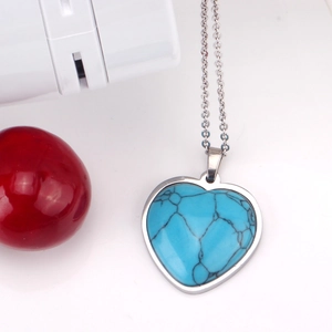 Detalle de colgante de corazón en turquesa azul sobre cadena de acero inoxidable plateado