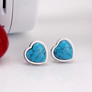 Detalle macro de pendientes de piedra en forma de corazón con borde plateado y mármol