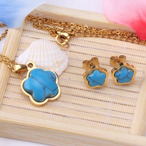 Detalle del conjunto de joyas con flores azules, collar y pendientes en bandeja bambú