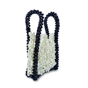 Detail of handmade beaded handbag with white pearl flowers and black faceted glass beads