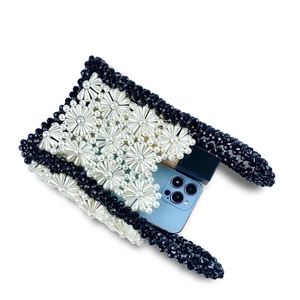 Detail of handmade daisy pearl woven handbag showing interior storage for phone and lipstick