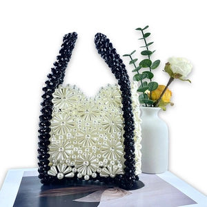 Detailed view of handmade beaded daisy handbag with white pearls and black faceted accents