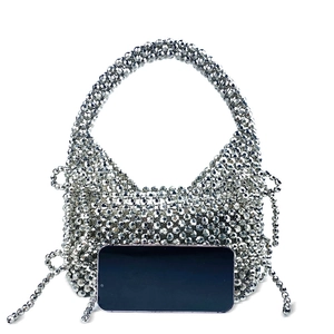 Sac à main argenté perlé avec franges, présenté à côté d'un smartphone pour la taille