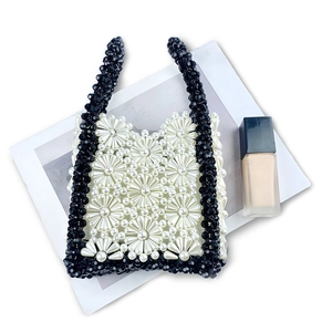 Detailed close-up of handmade beaded handbag with white floral patterns and black accents