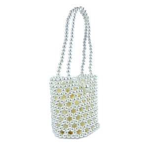 Detail of white beaded bucket bag featuring pearl woven lattice and silk inner pouch