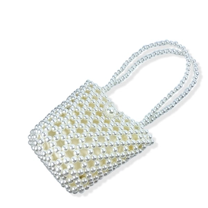 Close-up of handmade white pearl bucket bag with woven beaded texture and top handle