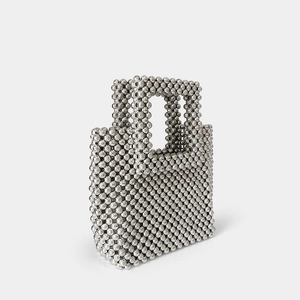 Detailed side view of silver beaded handbag showing woven metallic texture and structure