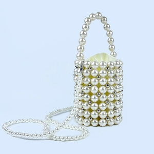 Detail of beaded pearl bucket bag with silver metal accents and satin drawstring lining