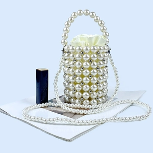Detail of beaded pearl bucket bag with satin drawstring pouch and elegant pearl chain