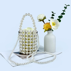 Detail of a handmade pearl beaded bucket bag with elegant woven texture and crossbody strap