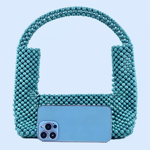 Detail of turquoise beaded handbag with U-shaped handle and phone for size reference