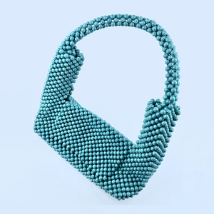 Macro detail of turquoise beaded handbag showing handmade weaving and texture