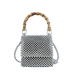 Detailed macro view of a silver beaded mini bag with a vintage bamboo handle and chain