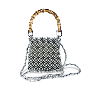Detail of silver metallic beaded handbag featuring a vintage bamboo top handle and chain