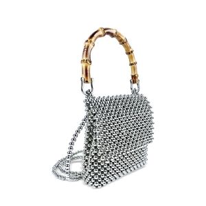 Detailed shot of handmade silver beaded bag featuring a natural polished bamboo handle