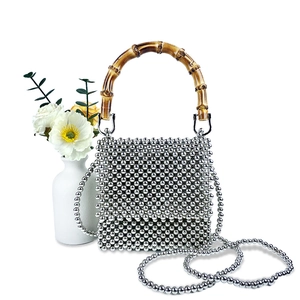 Detail of silver beaded mini handbag with natural bamboo handle and long chain strap
