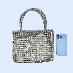 Detail of silver beaded tote bag with metallic sequins shown beside a phone for scale
