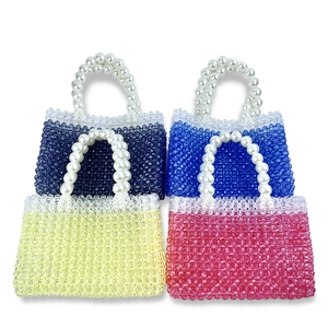 Detailed shot of four colorful beaded mini handbags featuring gradient tones and pearl handles