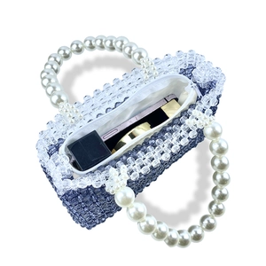 Detail of handmade beaded square handbag featuring blue beads and a white pearl handle