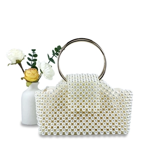 Detail of beaded pearl handbag featuring a gold metal ring handle and secure zipper closure