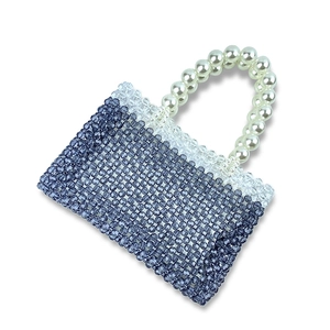 Detailed view of dark blue beaded handbag with large white faux pearl handle