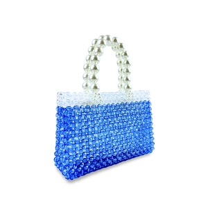 Detail of blue beaded handmade bag featuring large white faux pearl handle and acrylic beads