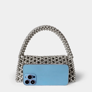 Silver beaded woven handbag next to a smartphone showing its mini compact size