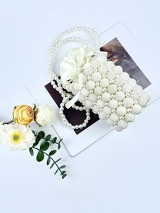 Elegant pearl bucket bag with satin drawstring and long shoulder strap on floral background